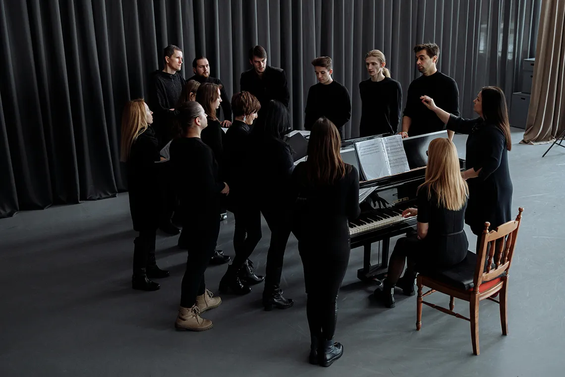 students rehearsing around a piano