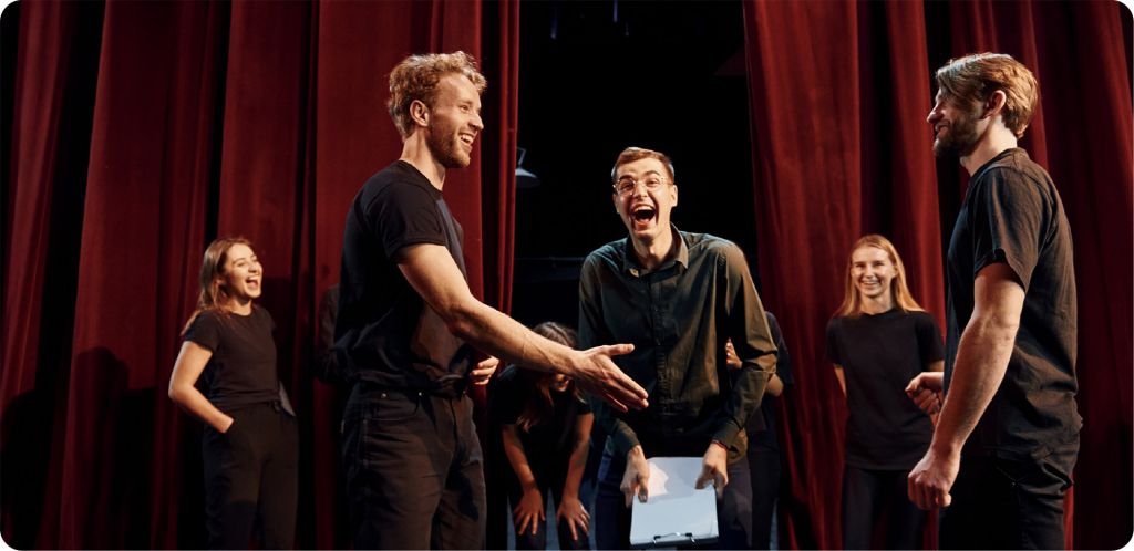 KD_Website-Image_Featured_News Actors smiling while performing on stage in street clothes